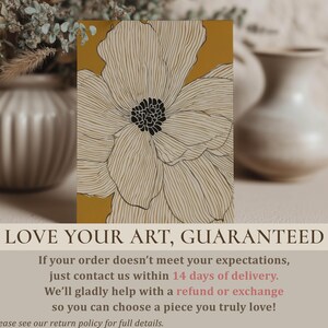 Close-up modern botanical linework flower in white and warm yellow with dark center, physical wall art print styled on a tabletop with soft vases blurred behind.