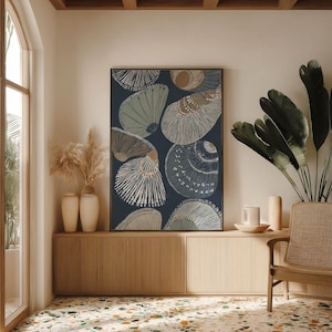 Scandinavian-style seashell poster in navy, beige, and muted gray with a calm mood, centered above a low cabinet with greenery and a woven chair.