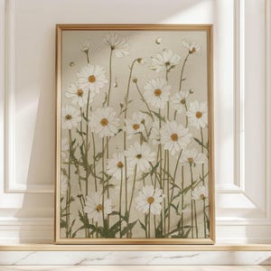 Soft vintage botanical wall art print of white daisies with sage green stems on a beige textured background, shown framed on a marble ledge by a paneled wall.