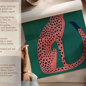 Bold art print of a pink cheetah on teal being unrolled on a neutral tabletop, with hands visible and overlay text about archival pigment printing and secure packaging.