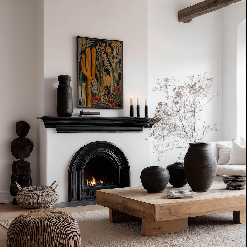 Muted desert botanical art print in deep black, yellow and rust, inviting mood; framed art print above a black fireplace mantel in a cozy neutral living room with a lit fire and woven accents.