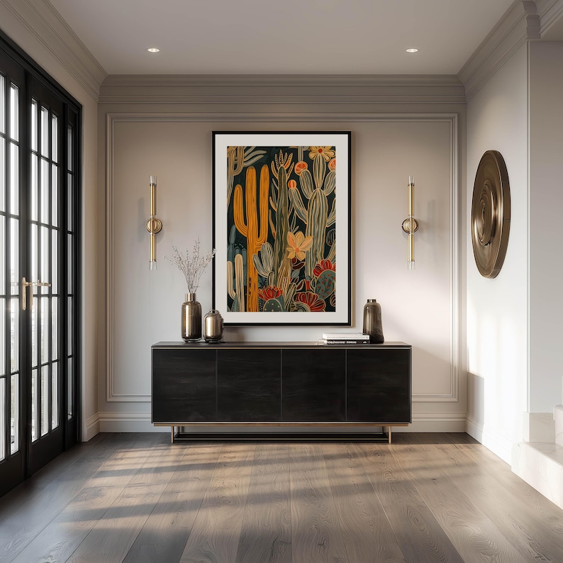 Detailed desert botanical art print in dark background with mustard and rust accents, rich layered mood; large framed art print above a sleek black console in an elegant entryway with brass wall decor and double glass doors.