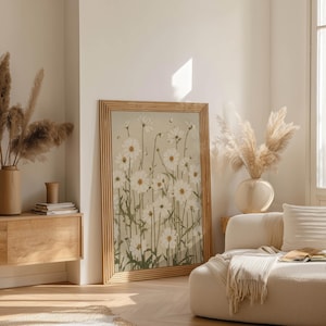 Delicate daisy poster in a vintage sketch style with white petals and sage stems on beige, placed in an airy living room scene near a wood sideboard and pampas.