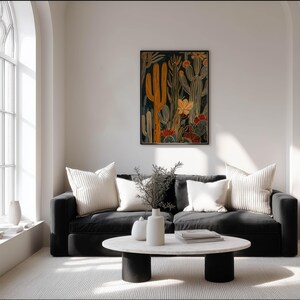 Modern cactus wall art print with mustard and muted teal, sophisticated cozy mood; framed art print on a soft white wall in a bright living room with a black sofa, arched window and round stone coffee table.