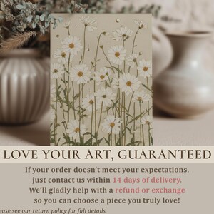 Close-up wall art print of a daisy meadow with white blooms and sage green stems on beige, styled on a tabletop with blurred vases and a guarantee overlay.