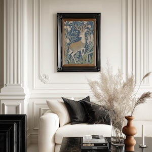 Elegant stag among blue and green foliage art print in a black frame centers an ornate paneled wall above a cream sofa with pampas grass and warm vases.