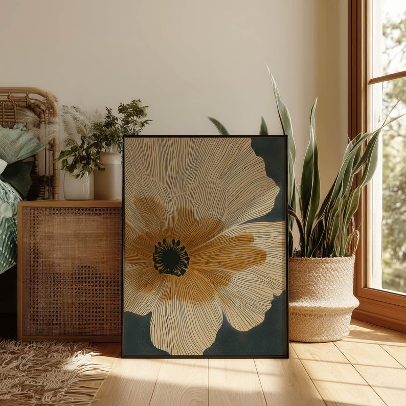 Botanical bloom wall art print in cream, ochre, and charcoal with fine contour lines and a calm modern feel, styled in a cozy bedroom corner by a window.