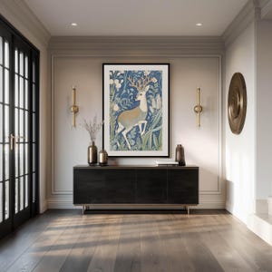 Artful blue deer with tan antlers in a lush floral pattern wall art print is framed above a sleek black console in an elegant entryway with brass accents.