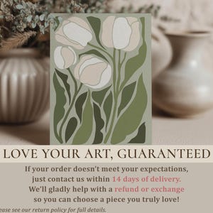Elegant botanical poster in muted green and cream with a serene mood, large framed poster hanging above a light wood dining table with cane-back chairs and ceramic vases.