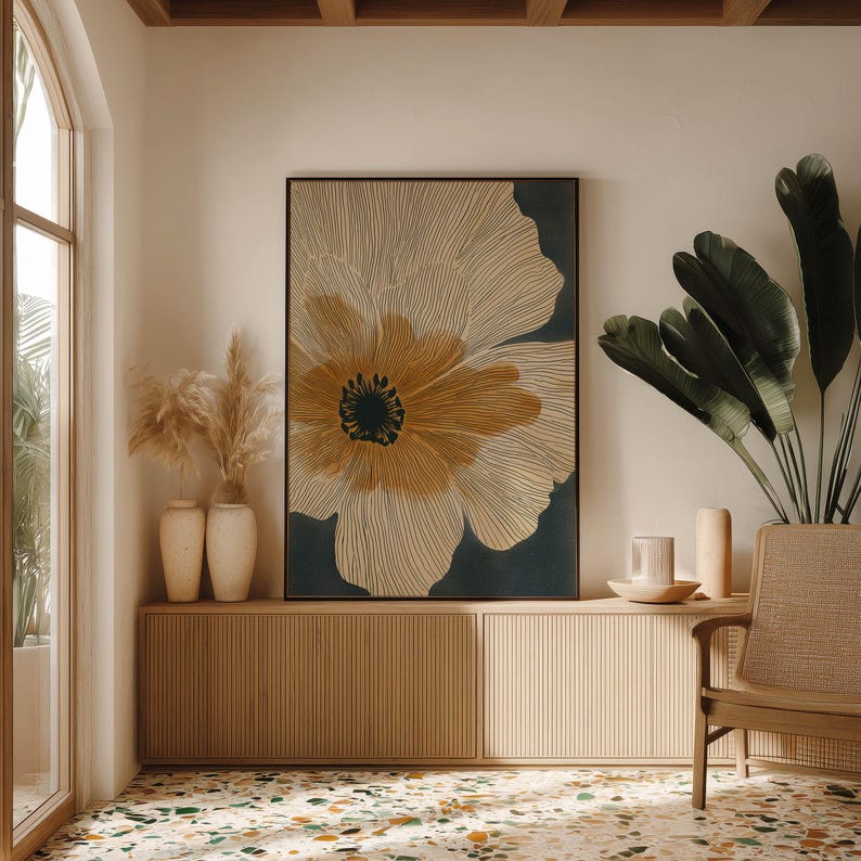 Neutral floral poster in cream and charcoal with an ochre center, minimalist and calming mood, centered above a low cabinet in a bright styled corner.