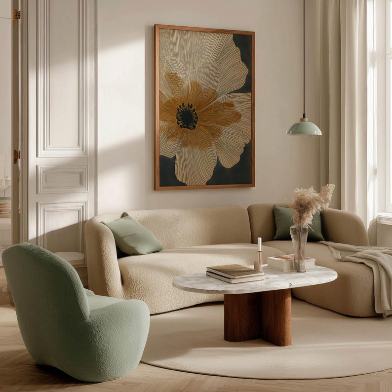 Contemporary linework flower art print in beige and black with warm golden accents, serene graphic look, framed above a curved sofa in a cozy living room.