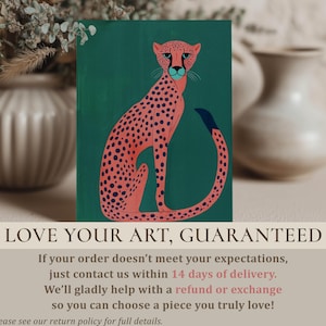 Graphic art print showing a pink cheetah with navy spots on teal, smaller print standing on a soft-toned surface with blurred ceramic vases and a "Love your art, guaranteed" overlay.