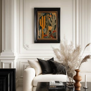 Elegant cactus poster in dark background with mustard highlights and floral shapes, refined botanical mood; framed print centered on an ornate paneled wall above a cream sofa styled with black cushions and pampas grass.