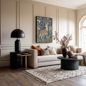 Storybook-style deer in blue floral forest wall art print is framed above a beige sofa in a warm living room with a patterned rug and earthy vases.