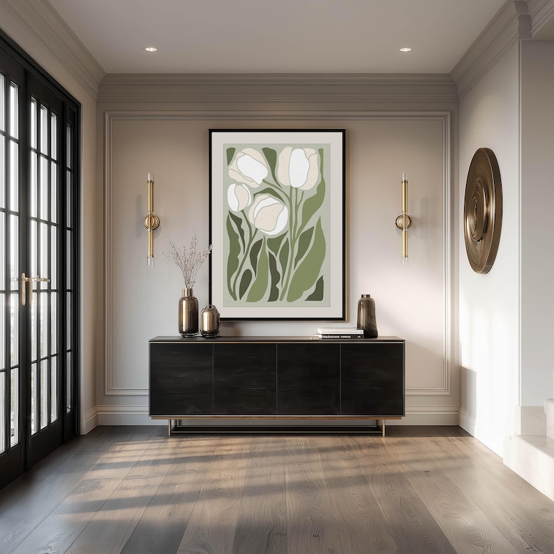 Large botanical art print in soft greens and cream with a sophisticated modern mood, framed above a sleek black console in an elegant entryway with brass accents and double glass doors.