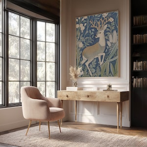 Charming blue woodland deer botanical poster hangs above a rustic wooden desk in a bright home office with tall windows and built-in bookshelves.