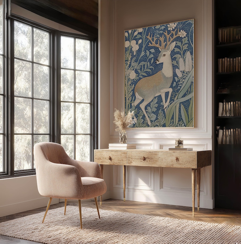 Charming blue woodland deer botanical poster hangs above a rustic wooden desk in a bright home office with tall windows and built-in bookshelves.