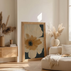 Abstract floral poster in neutral beige and deep charcoal with a bold golden center, minimalist and airy vibe, displayed in a bright living room near a sideboard.
