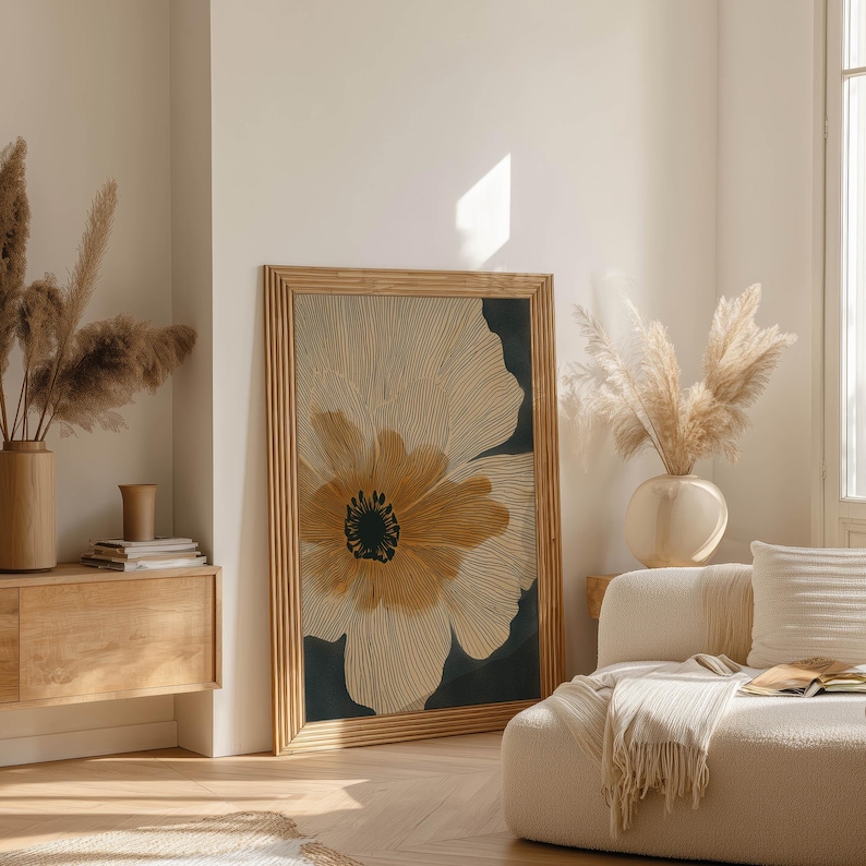 Abstract floral poster in neutral beige and deep charcoal with a bold golden center, minimalist and airy vibe, displayed in a bright living room near a sideboard.