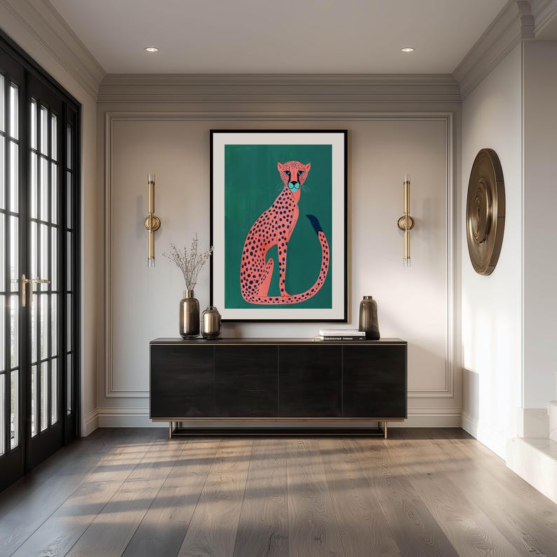 Stylish art print of a pink spotted cheetah on a teal field, large framed above a sleek black console in an elegant entryway with brass accents and double glass doors.