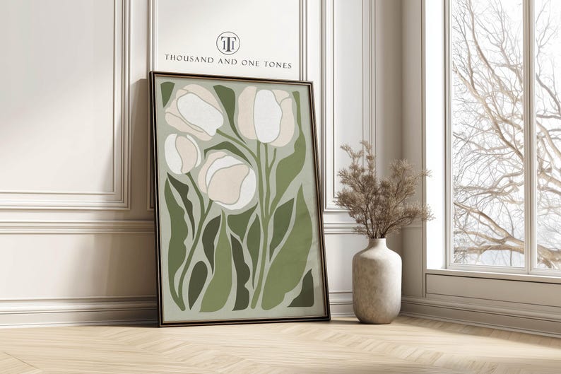 Stylized tulip art print in sage greens and cream with a calm modern mood, physical wall art print leaning against a white paneled wall beside a tall window and a vase of dried branches.