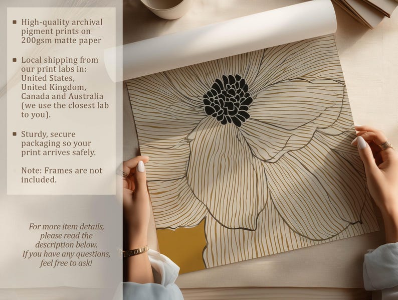Unrolled art print showing a white linework flower on mustard yellow, crisp modern style, photographed on a tabletop with hands and paper details visible.