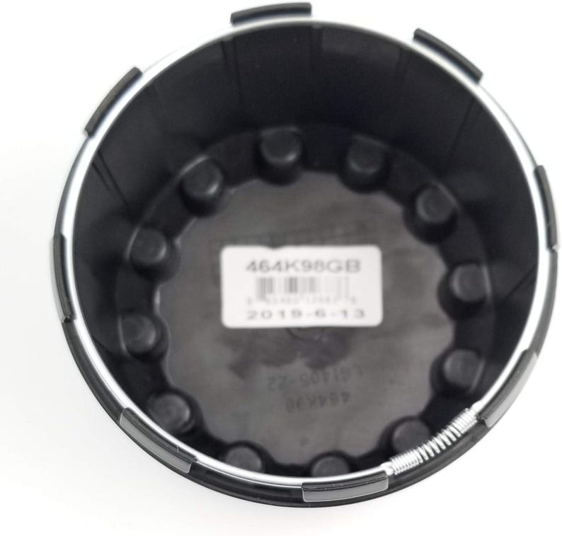 Pu&ograve; includere: Componente automobilistico in plastica nera con finiture argentate. La parte presenta un design circolare con elementi circolari in rilievo e un'etichetta con il testo "464K98GB" e "2019-6-13".