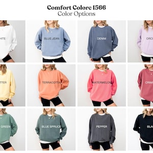 May include: A selection of Comfort Colors 1566 sweatshirts in various colors, including white, blue jean, denim, orchid, butter, terracotta, watermelon, crimson, light green, blue spruce, pepper, and black. Each sweatshirt has the color name printed on it.