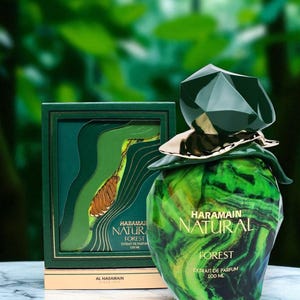 Peut inclure: Un flacon de parfum Al Haramain Natural Forest Extrait de Parfum 100 ml vert avec un bouchon vert foncé à facettes et une boîte rectangulaire assortie présentant des graphismes verts superposés et du texte doré, indiquant le volume.