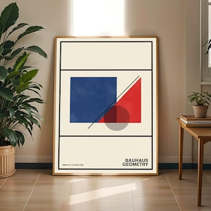 May include: Framed Bauhaus-style art print featuring geometric shapes in red, blue, and gray against a cream background. The print includes the text "Bauhaus Geometry" and "Simplicity & Structure" in black. The artwork is displayed in a wooden frame.