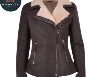 May include: A brown leather jacket with a cream-colored shearling collar and lining. The jacket has a diagonal zipper, two zippered pockets, and shearling cuffs. The Wildaura Jacket logo is in the upper left corner.