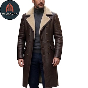 May include: A long, dark brown double-breasted coat featuring a wide, cream-colored shearling lapel and collar. The coat includes two rows of dark buttons, long sleeves, and two side pockets. It is worn over a grey turtleneck and dark trousers.
