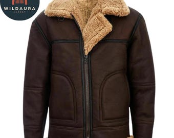 Puede incluir: Una chaqueta de cuero marrón oscuro con un grueso forro de borrego color canela, un cuello ancho con muescas y un cierre central de cremallera metálica. La prenda incluye detalles de ribetes de cuero negro, dos bolsillos y puños de borrego.