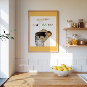 Puede incluir: Una impresión artística enmarcada con un borde amarillo presenta las palabras "pause here coffee time" sobre una ilustración de una taza de café. La impresión cuelga en una pared blanca sobre una encimera de madera con un cuenco de limones.