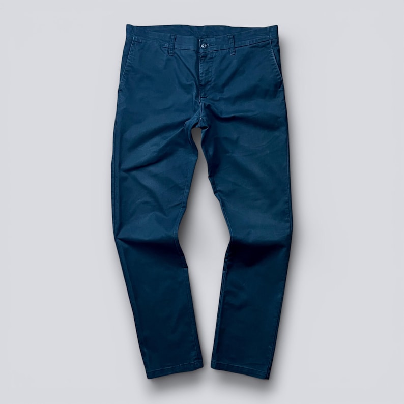 May include: A white ceramic mug with a black handle and the text "But First, Coffee" in a black, bold font. The mug is sitting on a wooden surface. The mug is approximately 4 inches tall.