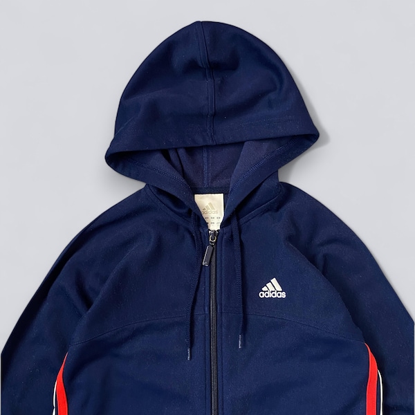 May include: Navy blue zip-up hoodie with a hood. The jacket features a white Adidas logo on the chest and red and white stripes down the side. The hoodie has a full zipper and a drawstring hood.