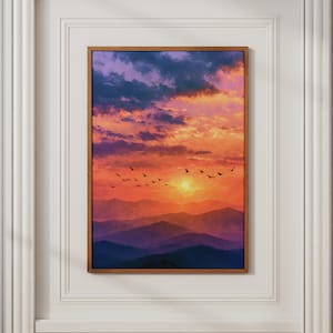 Könnte beinhalten: Ein rechteckiger Wandkunstdruck in einem dünnen Holzrahmen, der eine Sonnenuntergangslandschaft zeigt. Die Szene zeigt geschichtete violette und blaue Bergsilhouetten unter einem lebendigen Himmel voller orangefarbener, gelber und violetter Wolken.