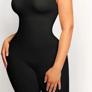 Puede incluir: Body negro sin mangas con cuello redondo. La prenda de una pieza tiene un diseño ajustado que se extiende hasta la parte superior de los muslos. La tela parece lisa y opaca, creando una silueta elegante. El body está diseñado para un ajuste ceñido.