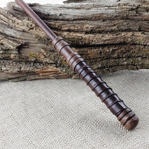 May include: A dark brown wooden wand with a textured grip and a rounded tip.