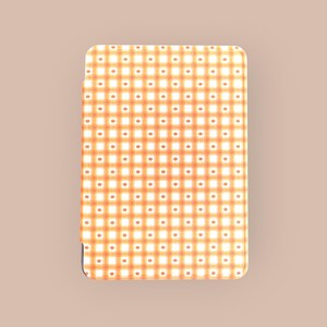 Puede incluir: Una cartera rectangular con un patrón de cuadros naranja y blanco repetido. Pequeños puntos naranjas están espaciados uniformemente dentro de cada cuadrado blanco. La cartera tiene esquinas redondeadas y un borde negro.