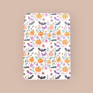 Puede incluir: Patrón rectangular blanco con temática de Halloween con calabazas naranjas sonrientes, murciélagos morados, flores rosas y blancas y hojas verdes. El diseño se repite en toda la superficie.