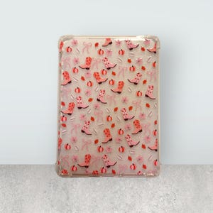 Puede incluir: Funda transparente para tableta con un patrón repetido de botas de vaquero rosas, lazos, calabazas y hojas. La funda tiene un borde transparente. El diseño combina temas otoñales y del oeste.