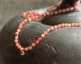 dainty sunstone necklace hand knotted on coral silk with gold ball charm and clasp