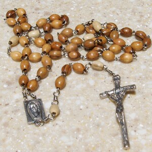 May include: A wooden rosary with brown and beige beads, a silver crucifix, and a silver pendant with a religious image.