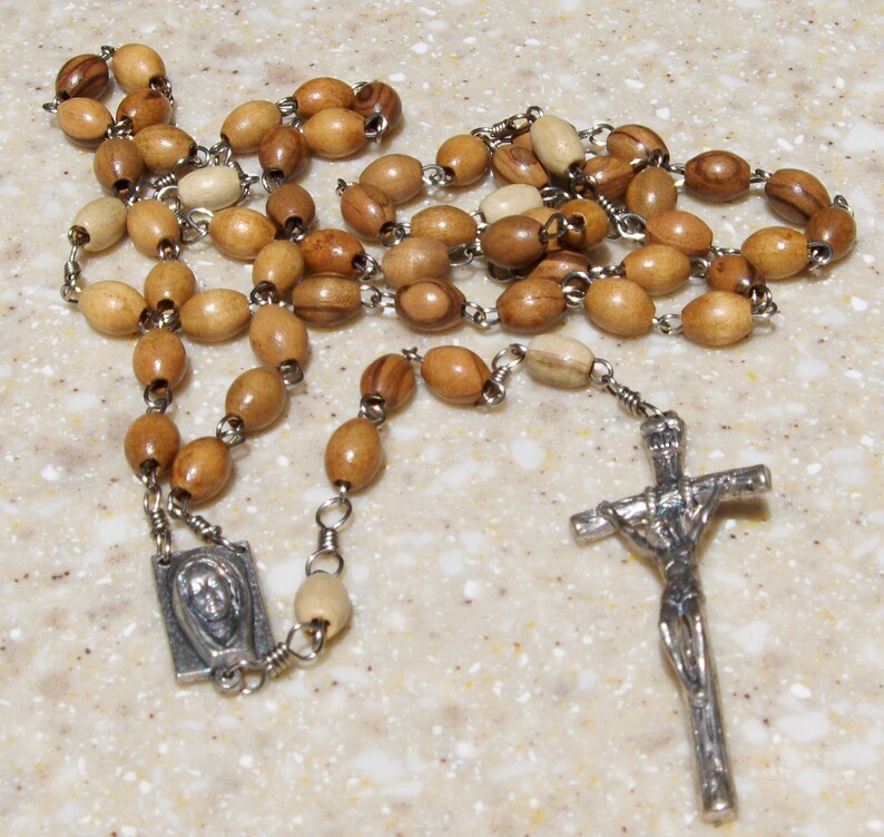May include: A wooden rosary with brown and beige beads, a silver crucifix, and a silver pendant with a religious image.