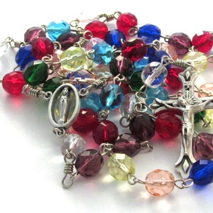 May include: A colourful glass bead rosary with a silver cross and a silver charm of the Virgin Mary. The beads are in shades of red, blue, green, yellow, and purple.