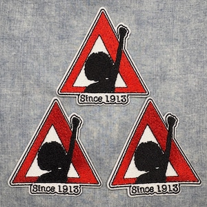 May include: Three embroidered patches featuring a red triangle with a white interior and a black silhouette of a person with a raised fist. The text "Since 1913" is below the silhouette. Patches are on a blue denim background.