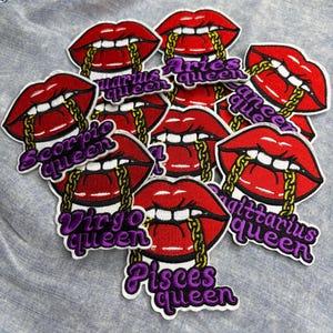 May include: Embroidered patches featuring red lips with gold chain details and various zodiac sign names in purple script, including "Aries Queen," "Virgo Queen," and "Pisces Queen."