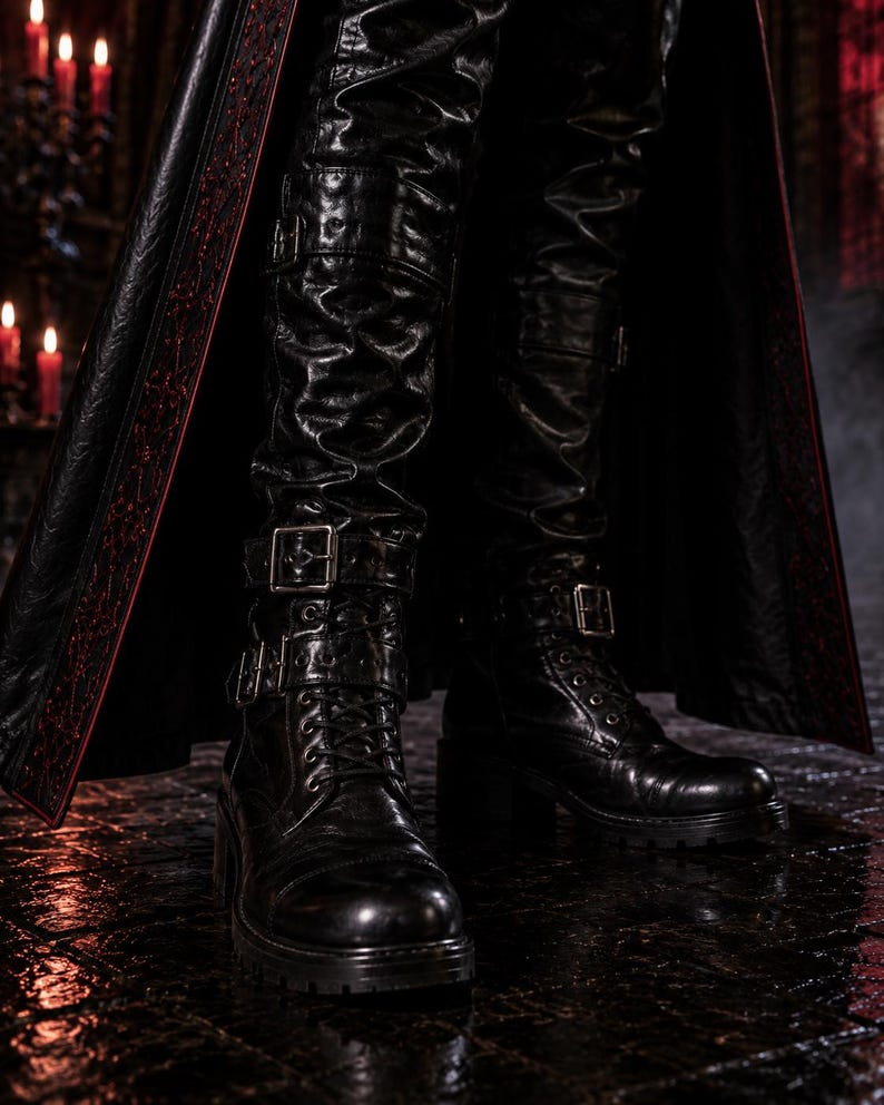 May include: Black leather boots with buckles and laces. The boots are worn with black leather pants and a long black coat with red trim. The image has a dark, gothic aesthetic.