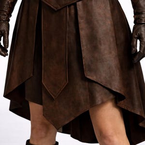 May include: A brown leather skirt with a layered, asymmetrical design. The skirt features a detailed belt and is paired with matching gloves and boots. The overall style suggests a medieval or fantasy theme.